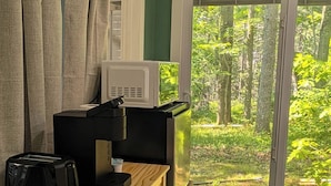 Una habitación con un aparador de madera, microondas, tostadora y una puerta corrediza de vidrio que da a un jardín.
