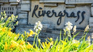 Un mur de pierre sur lequel est gravé en lettres noires le nom « Rivergrass ».
