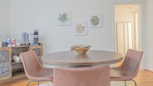 A dining area with a round table, two chairs, and a coffee machine.