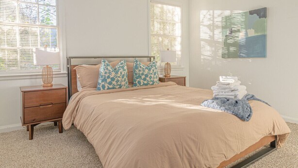 A bedroom with a bed, nightstands, a lamp, and a painting on the wall.