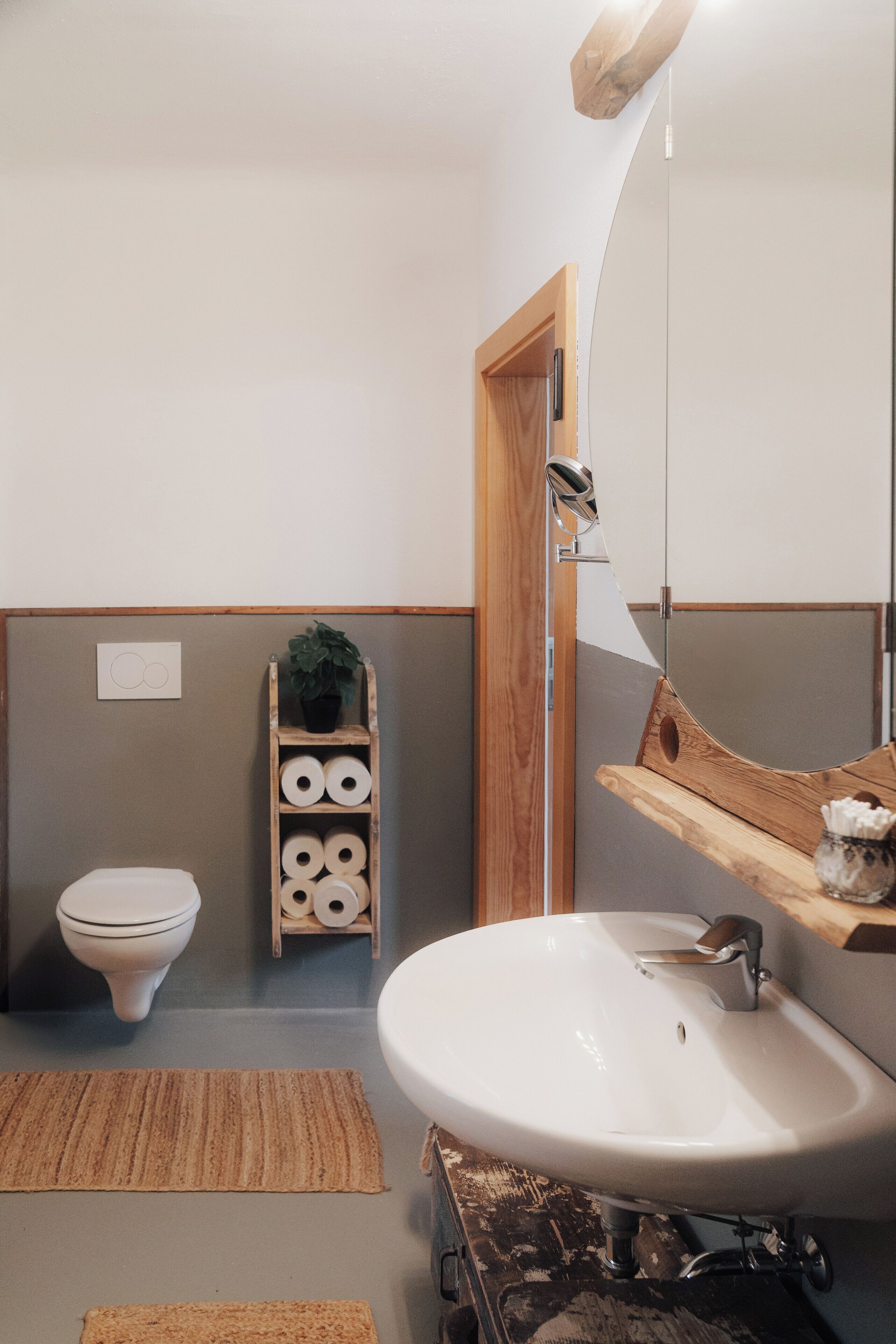 Un baño con un lavabo blanco, estantes de madera, un inodoro y un armario de madera con toallas.