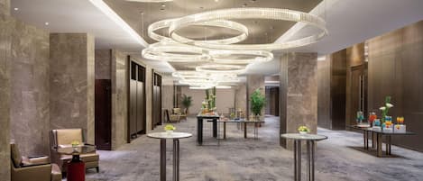 A spacious lobby with a modern chandelier, seating areas, and a reception desk.