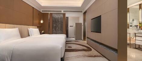 A hotel room with a large bed, a TV mounted on the wall, and a bathroom with a mirror and sink.