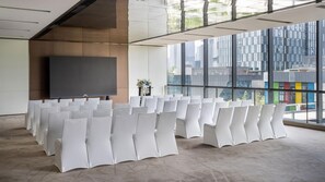 A conference room with rows of white chairs, a large flat-screen TV, and a large window with a city view. - Intercontinental Zhengzhou Zhengdong, by IHG (Zhengzhou)