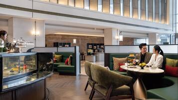 Un moderno vestíbulo de hotel con zonas de estar, mostrador de recepción y una vitrina de vidrio.