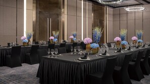 A conference room with long tables set for a formal event, featuring floral centerpieces and a modern chandelier. - Intercontinental Zhengzhou Zhengdong, by IHG (Zhengzhou)