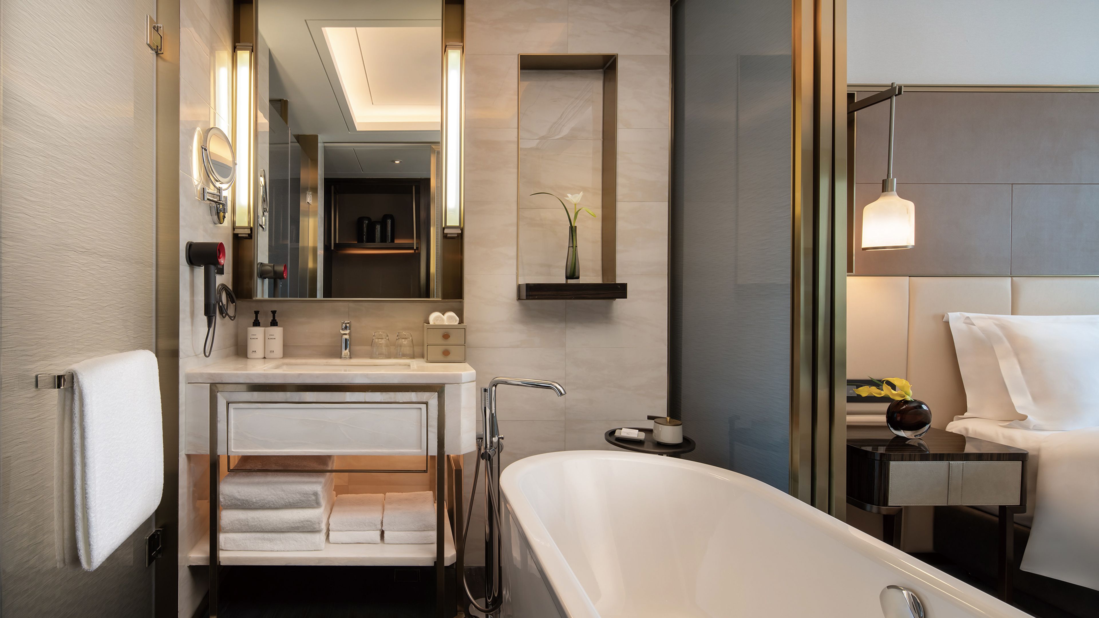 Une salle de bain moderne avec une baignoire sur pieds, un meuble-lavabo avec un miroir et une étagère contenant des articles de toilette.