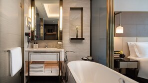 Une salle de bain moderne avec une baignoire sur pieds, un meuble-lavabo avec un miroir et une étagère contenant des articles de toilette.