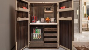 Eine kompakte Küchenzeile mit Kühlschrank, Kaffeemaschine und einer kleinen Obstauslage.