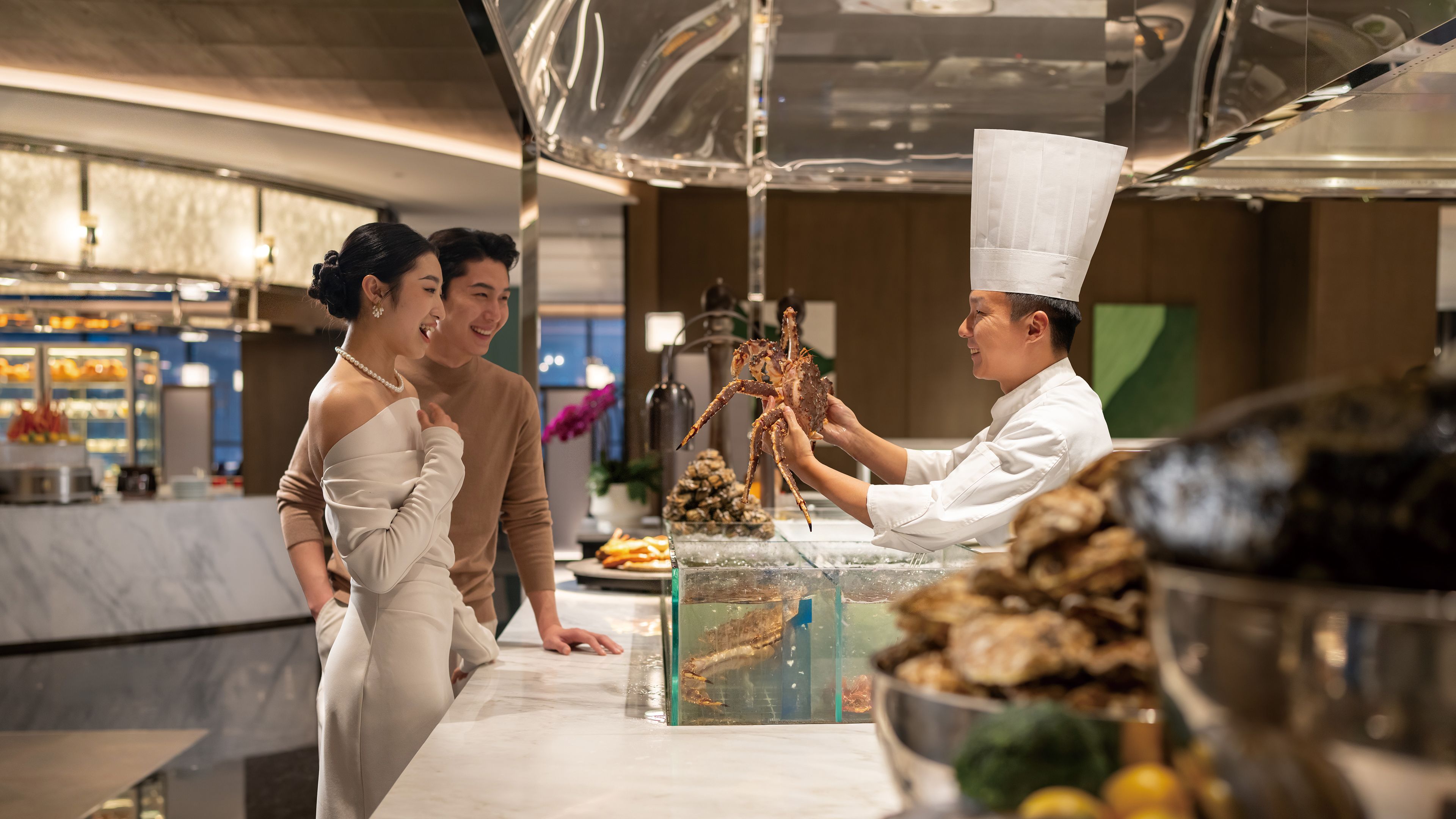 A seafood display with a crab, a chef, and two diners in a restaurant setting.