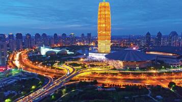 A cityscape with a prominent, illuminated tower, a roundabout with multiple exits, and surrounding high-rise buildings.
