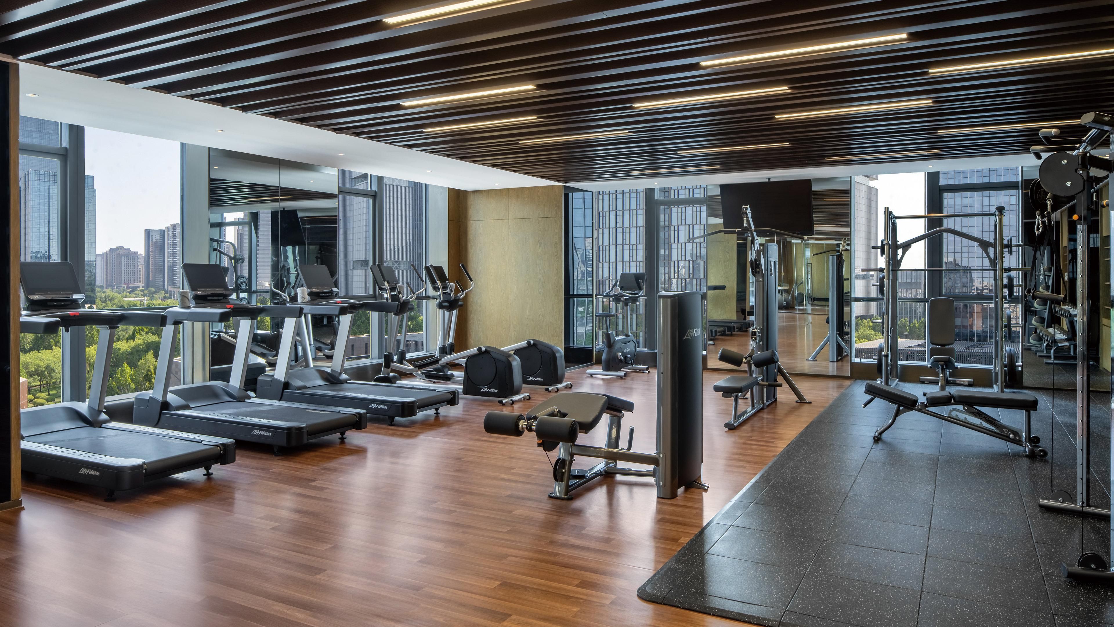 Un gimnasio moderno con cintas de correr, máquinas de pesas y un espejo grande.