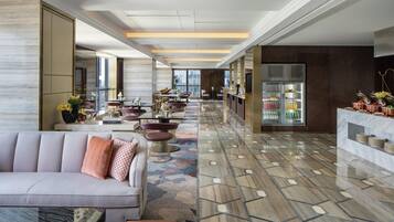 Un moderno vestíbulo de hotel con una larga recepción, zona de estar y bufé.