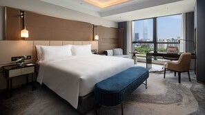 Une chambre d’hôtel moderne dotée d’un grand lit, d’un bureau avec un piano, d’une vue sur la ville et d’une grande fenêtre.