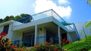 A two-story building with a balcony and a covered porch area. - Villa with sea view in the heart of Sainte-Anne (Martinique)