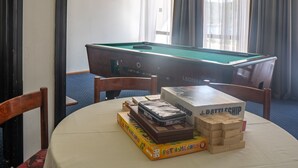 A pool table with a green felt surface, surrounded by wooden chairs. There are several board games and a box of wooden blocks on the table. - Hotel Issa - Double Room Park View 26 (Vis)