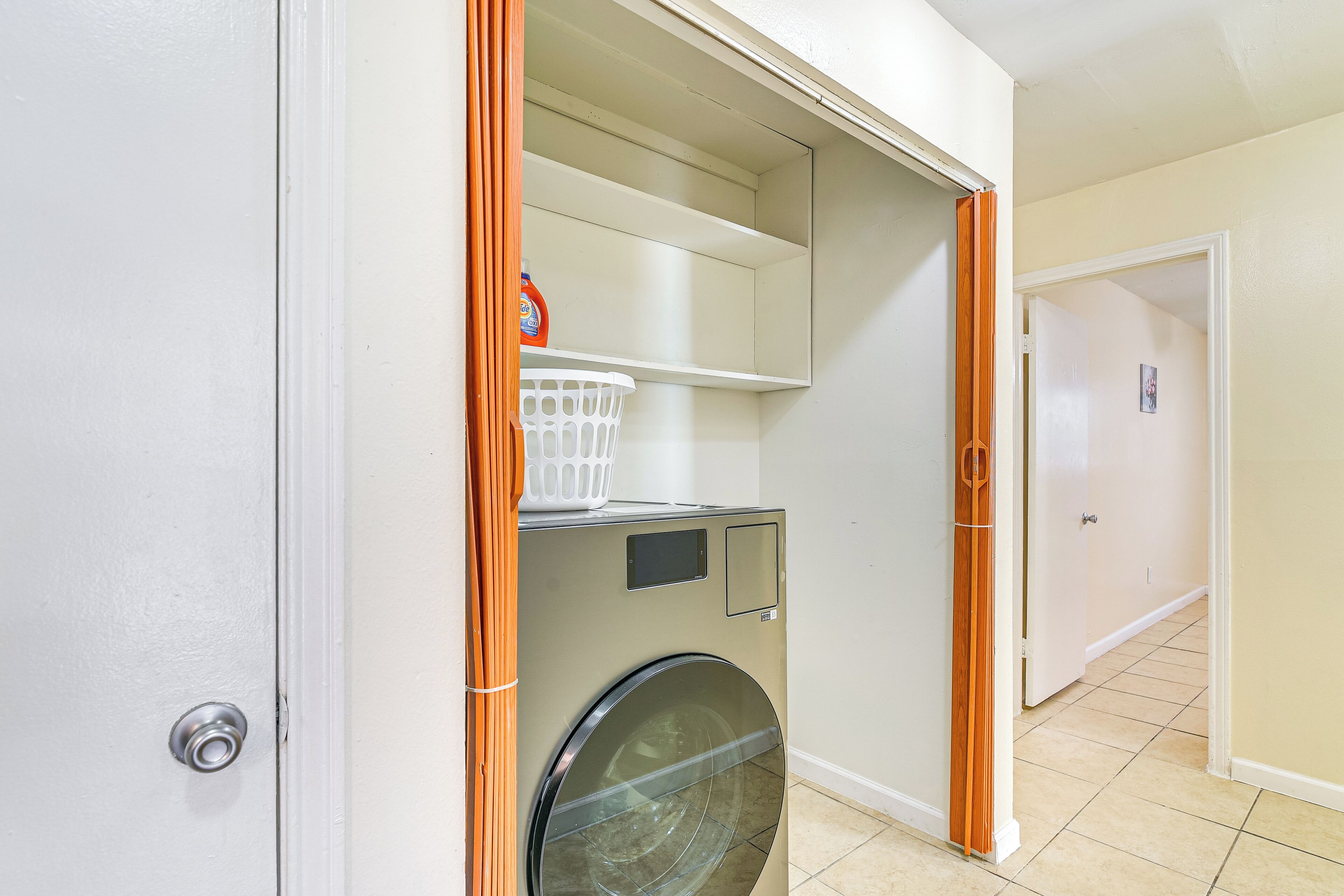 Une buanderie équipée d’un lave-linge, d’un panier et d’une étagère.