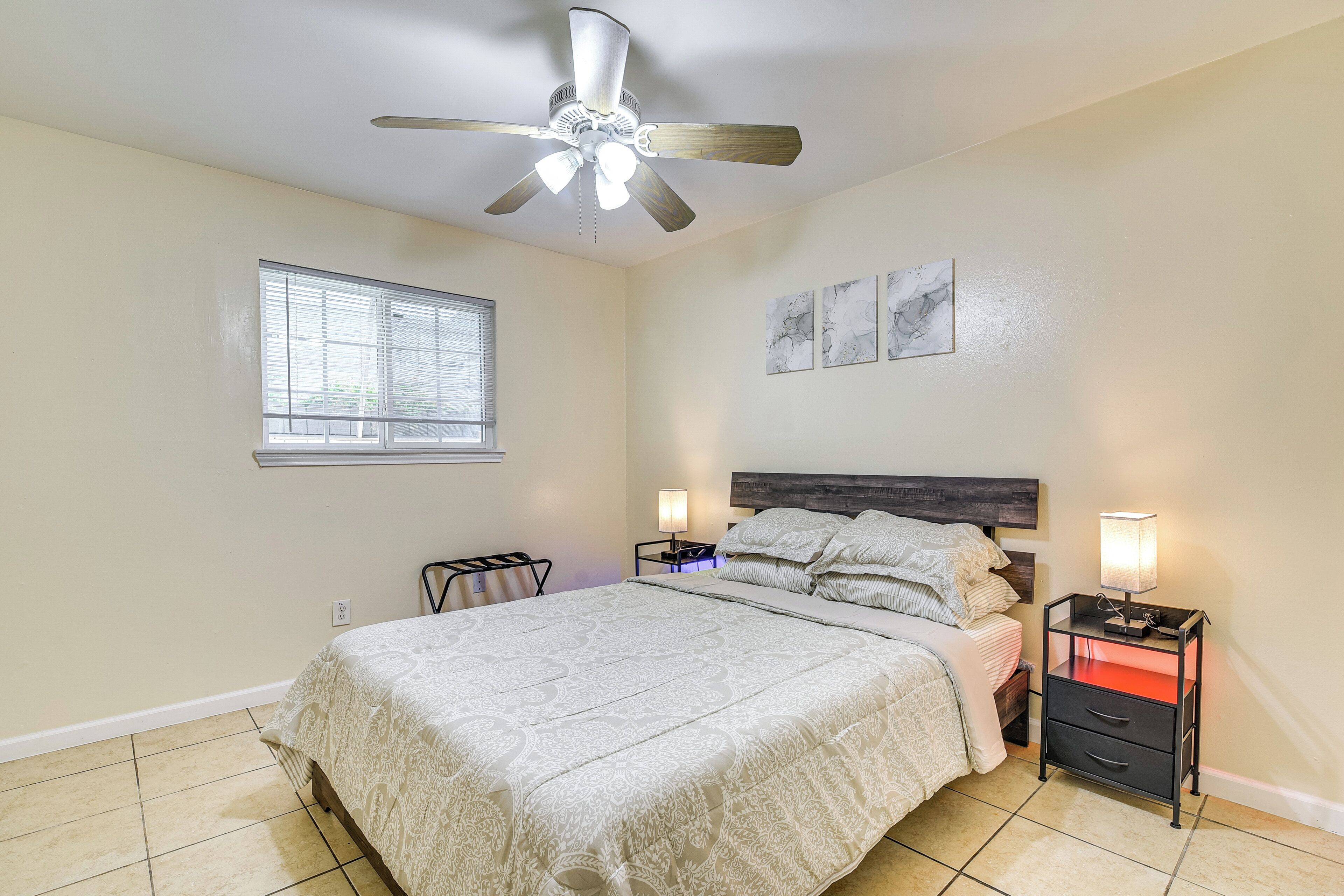 A bedroom with a bed, a ceiling fan, a nightstand, and a window.