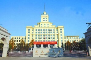 A large, multi-story building with a prominent entrance and a flagpole. - Homeinn Ripple Hotel (Harbin Xuefu Road Kaide Plaza) (Harbin)