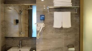 Un baño con lavamanos, espejo, ducha y toallero.