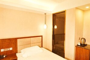 A hotel room with a bed, a nightstand, a lamp, and a door leading to a balcony.
