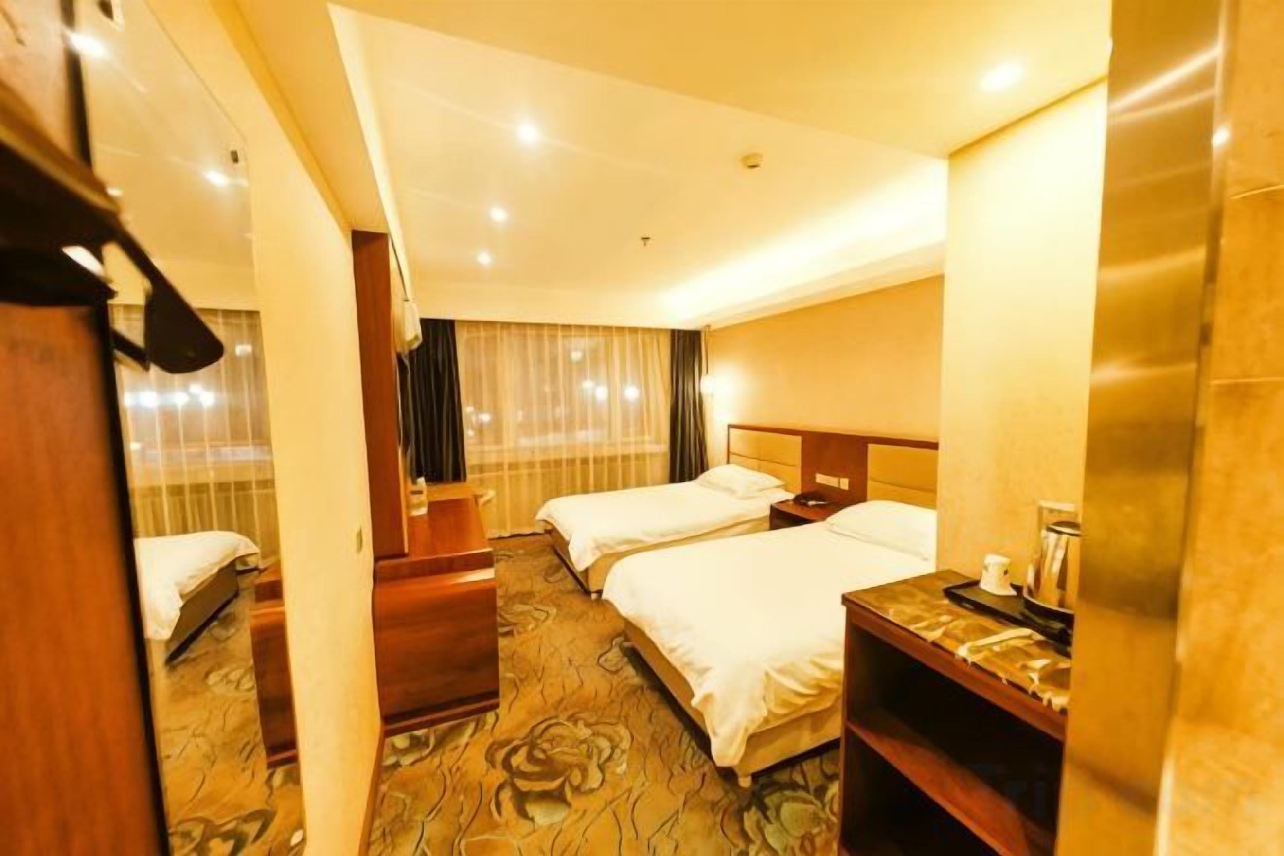 Habitación de hotel con dos camas, un escritorio y un espejo.