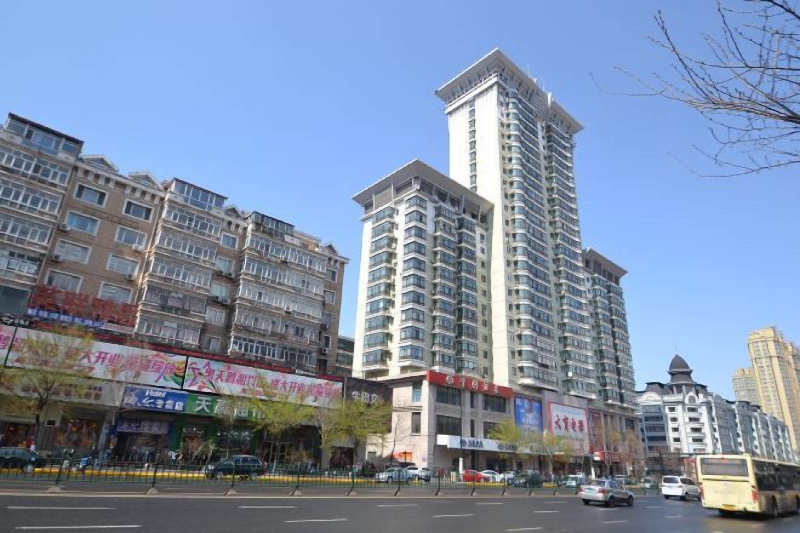Un edificio de varios pisos con una torre central destacada, rodeado de otros inmuebles residenciales.