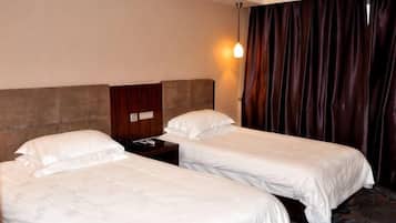 Una habitación de hotel con dos camas individuales, una mesita de noche, una lámpara y una cortina.