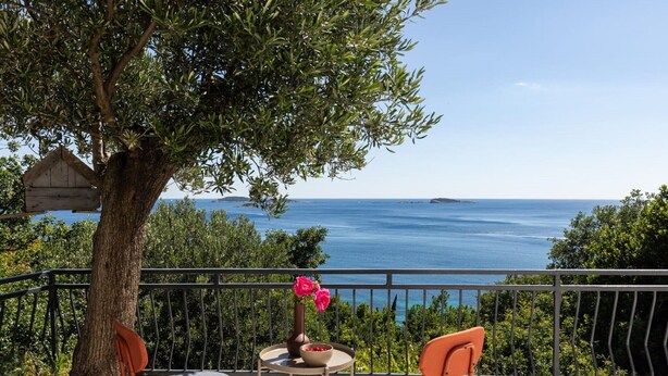 A balcony with two chairs, a small table, and a vase of flowers.