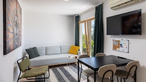 A modern living room with a grey sofa, a small table, and a TV mounted on the wall.