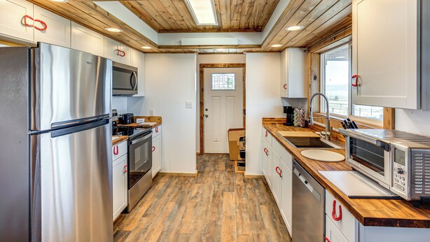 Eine moderne Küche mit Holzbalkendecke, Edelstahlgeräten und einer Holz Arbeitsplatte.