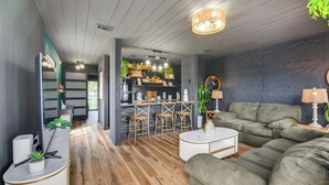 A modern living room with a sofa, coffee table, and bar area with stools. - Chic & Elevated Decor: Beachfront PCB Gem w/ Patio (Panama City Beach)