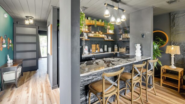 A modern kitchen with a central island, bar stools, and hanging pendant lights. - Chic & Elevated Decor: Beachfront PCB Gem w/ Patio (Panama City Beach)