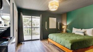 A bedroom with a green bed, a wooden floor, a balcony with a view, and a ceiling light fixture. - Chic & Elevated Decor: Beachfront PCB Gem w/ Patio (Panama City Beach)