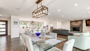 A modern kitchen with a central island, a dining area with glass tables, and a living room with a sofa and fireplace. - 2 Mi to Lake Poway: Mtn-View Escape w/ Patio! (Poway)