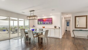 A modern kitchen with a glass dining table, white cabinets, and a large window overlooking a deck. - 2 Mi to Lake Poway: Mtn-View Escape w/ Patio! (Poway)