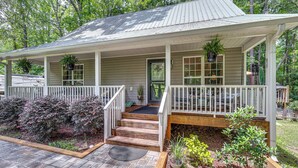 Ein zweistöckiges Haus mit Veranda, Holzstufen und einem Garten mit verschiedenen Pflanzen.