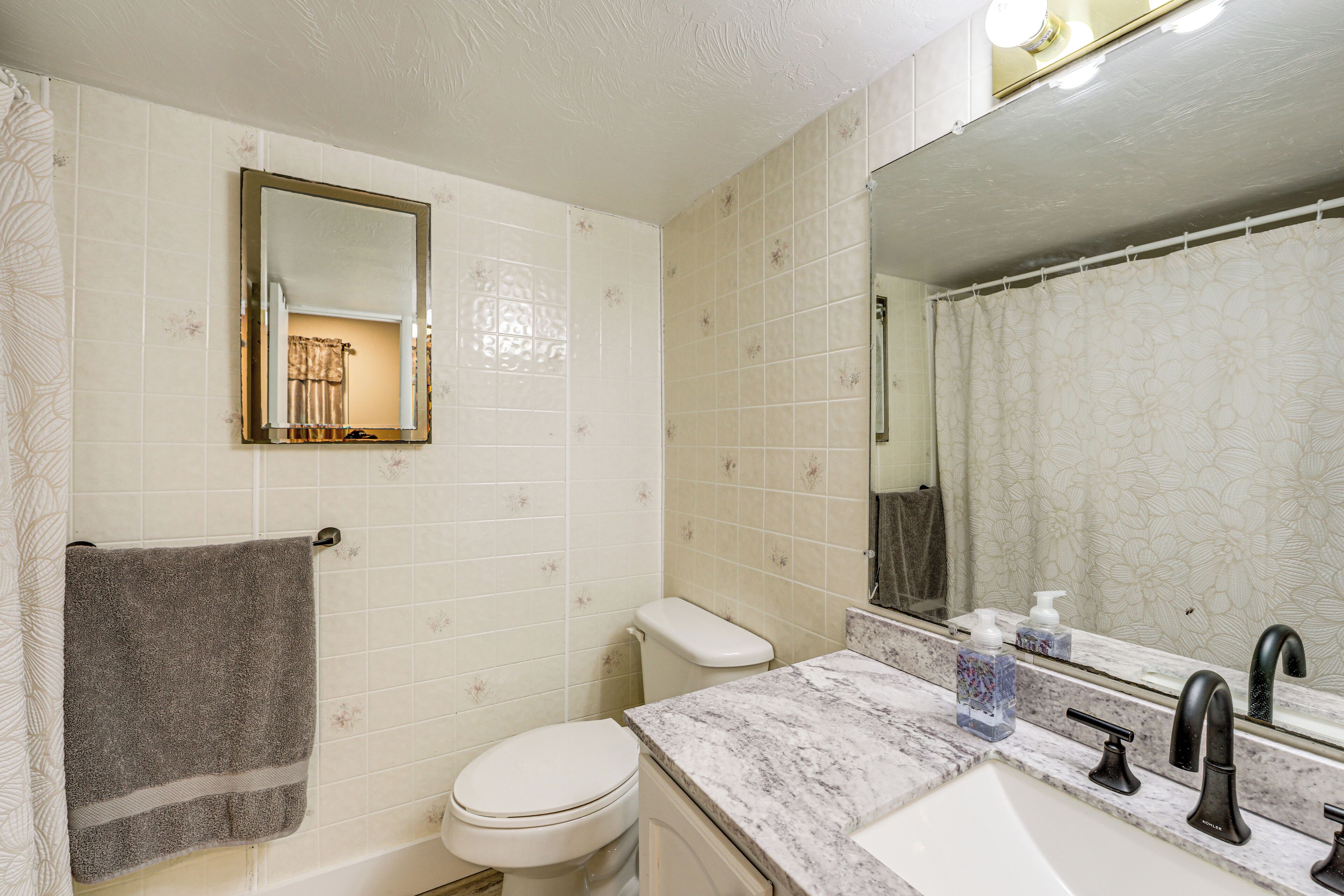Een badkamer met een toilet, een wastafel met spiegel en een handdoek aan de muur.