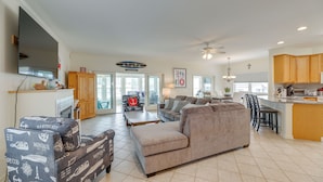 A spacious living room with a large sofa, a coffee table, and a dining area with a kitchen in the background. - Waterfront Gem w/ Dock: 3 Mi to Fenwick Island Fun (Selbyville)