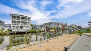 A waterfront property with a dock, a boat, and a modern multi-story house. - Waterfront Gem w/ Dock: 3 Mi to Fenwick Island Fun (Selbyville)