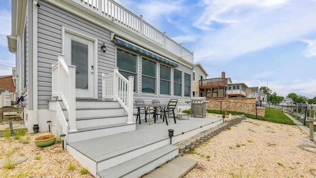 A house with a covered porch, outdoor seating, and a stone retaining wall. - Waterfront Gem w/ Dock: 3 Mi to Fenwick Island Fun (Selbyville)