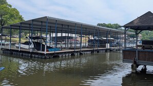 Ein überdachter Steg mit Booten, ein kleines Pavillon und ein Gewässer.