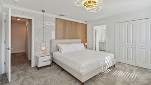 Une chambre à coucher avec un lit, des tables de chevet, un miroir et une armoire.