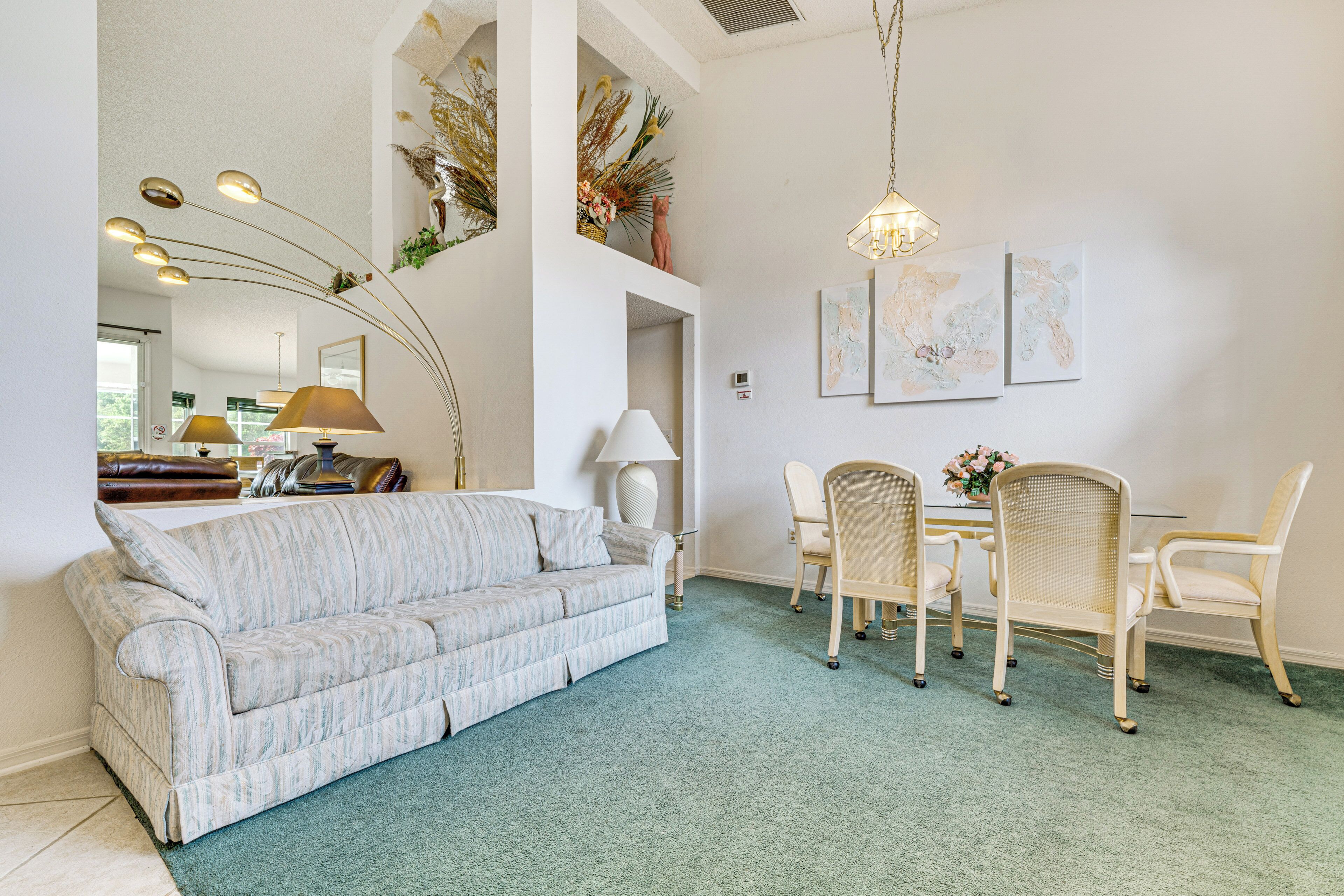 Ein geräumiges Wohnzimmer mit einer Couch, einem Esstisch, Stühlen und einer Deckenleuchte.