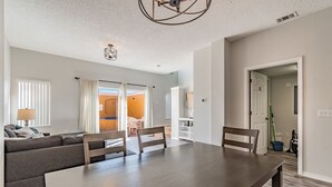 En moderne stue med spisebord, sofa og udsigt til det tilstødende køkken.