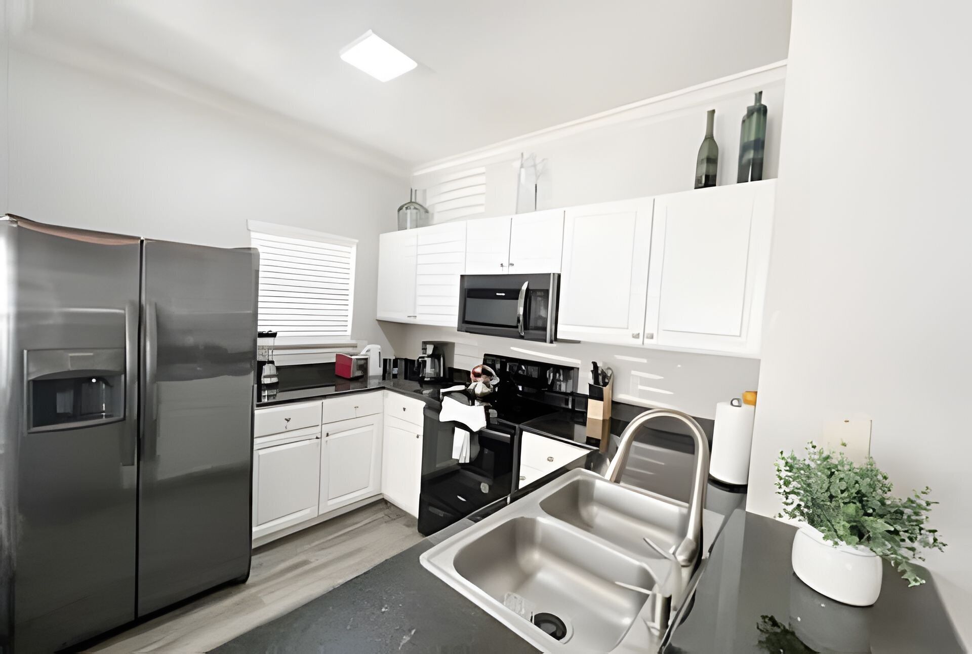A modern kitchen with white cabinets, stainless steel appliances, and a black countertop.