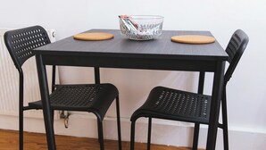 A black dining table with two chairs, a bowl, and a wooden coaster.