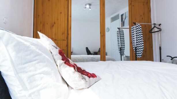 A bedroom with a bed, a wardrobe, and a mirror.