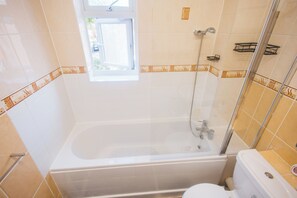 A bathroom with a bathtub, shower, and toilet.