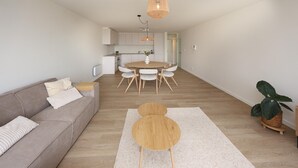 A modern living room with a sofa, a round wooden coffee table, and a dining area with a round table and chairs. - Lovely apartment in Oostende with WiFi (Oostende)